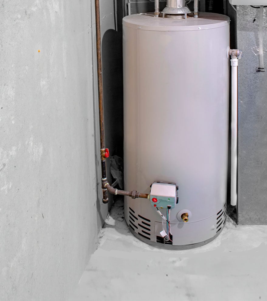 Grey water heater in a utility room with pipes, control box, and metal ductwork visible next to it.